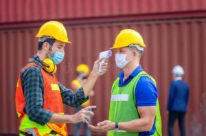 factory-worker-man-checking-fever-digital-thermometer-scan-protect-coronavirus-covid-cargo-containers-183296417-e1607607905118.jpg
